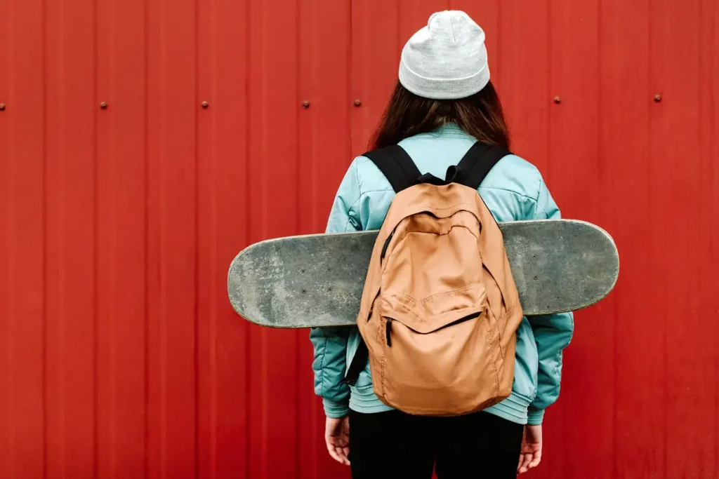 Horizontal Method: Girl with backpack carrying skateboard