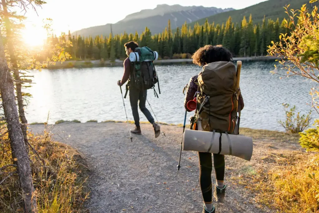 Couple backpacking on lakeside trail: For understanding about the importance of tent weight in backpacking