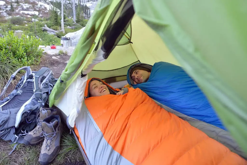 Couple relaxing in sleeping bags in tent