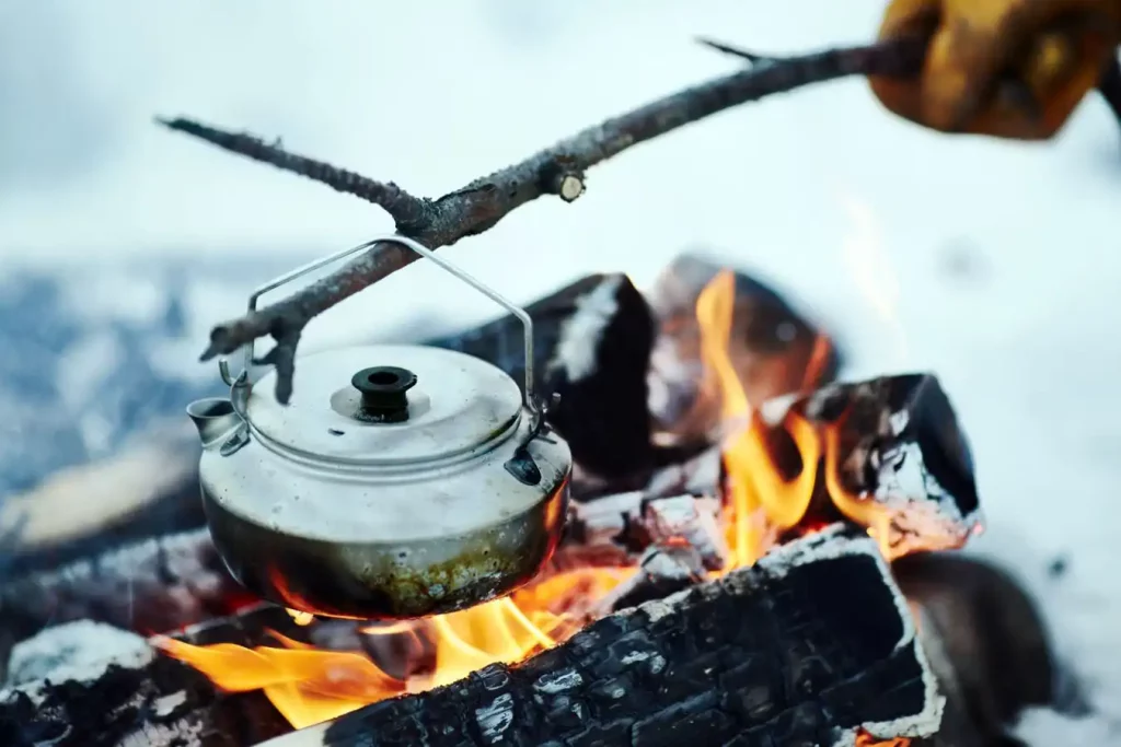 Kettle on stick over campfire, boiling water