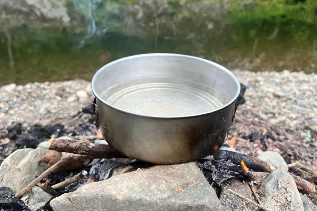 Water boiling in a cooking pot over campfire